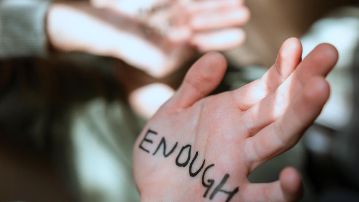 Foto van hand waar Enough op geschreven is