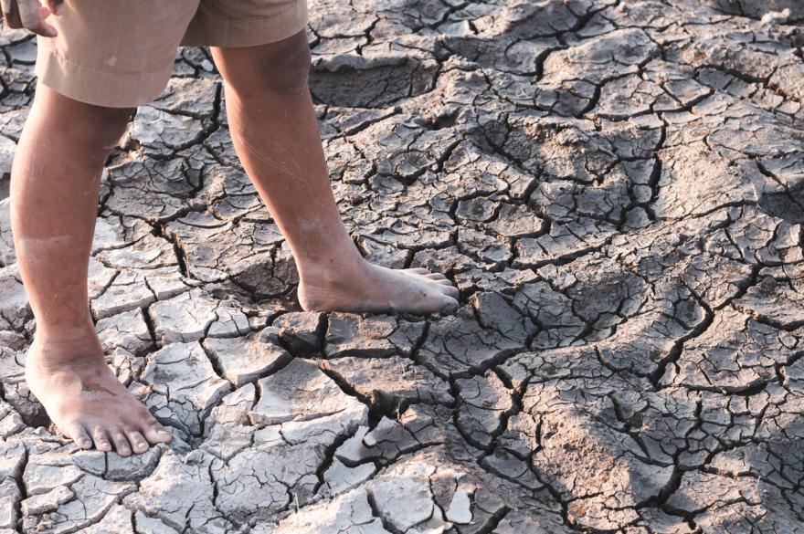 Kindervoeten op uitgedroogde barstende ondergrond